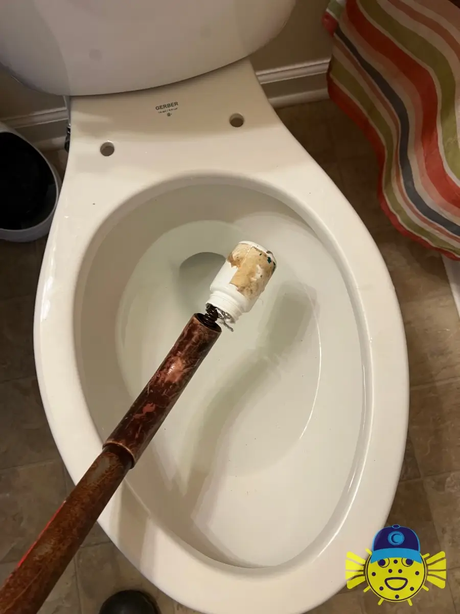 A Swell Guy Plumbing auger tool removing a clogged medicine bottle from a Gerber toilet bowl in Ladson, SC.