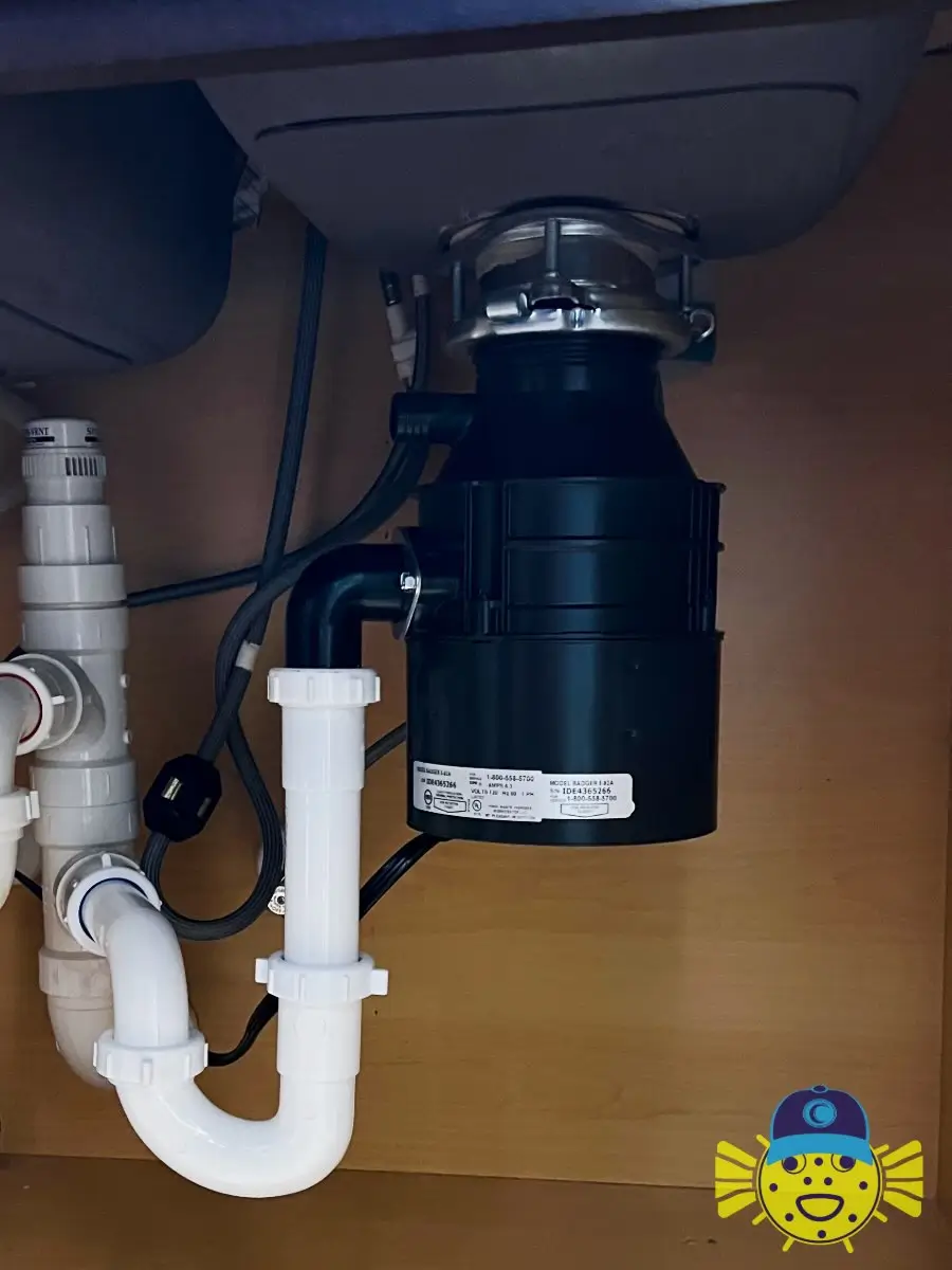 Newly installed InSinkErator Badger garbage disposal connected to under-sink PVC drainage piping by Swell Guy Plumbing.