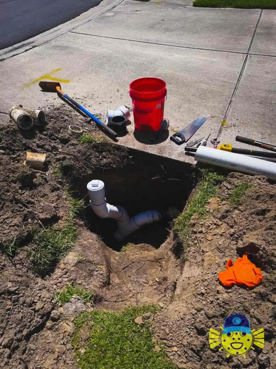 Swell Guy Plumbing sewer line clean-out installation showing PVC pipe fittings in ground next to tools in Hanahan, SC.