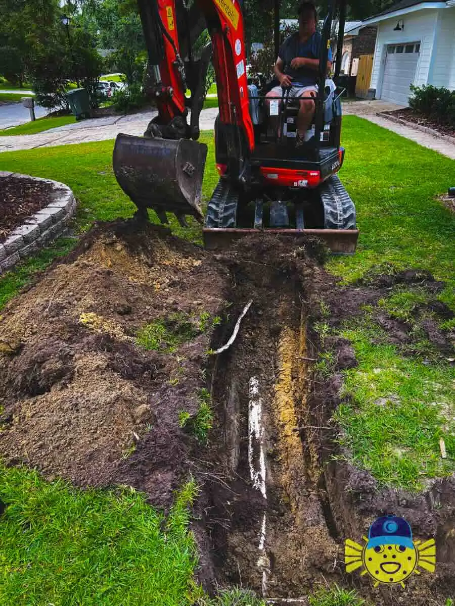 Swell Guy Plumbing technician operating a mini excavator to dig a trench for a sewer line replacement in a residential yard in Hanahan, SC.