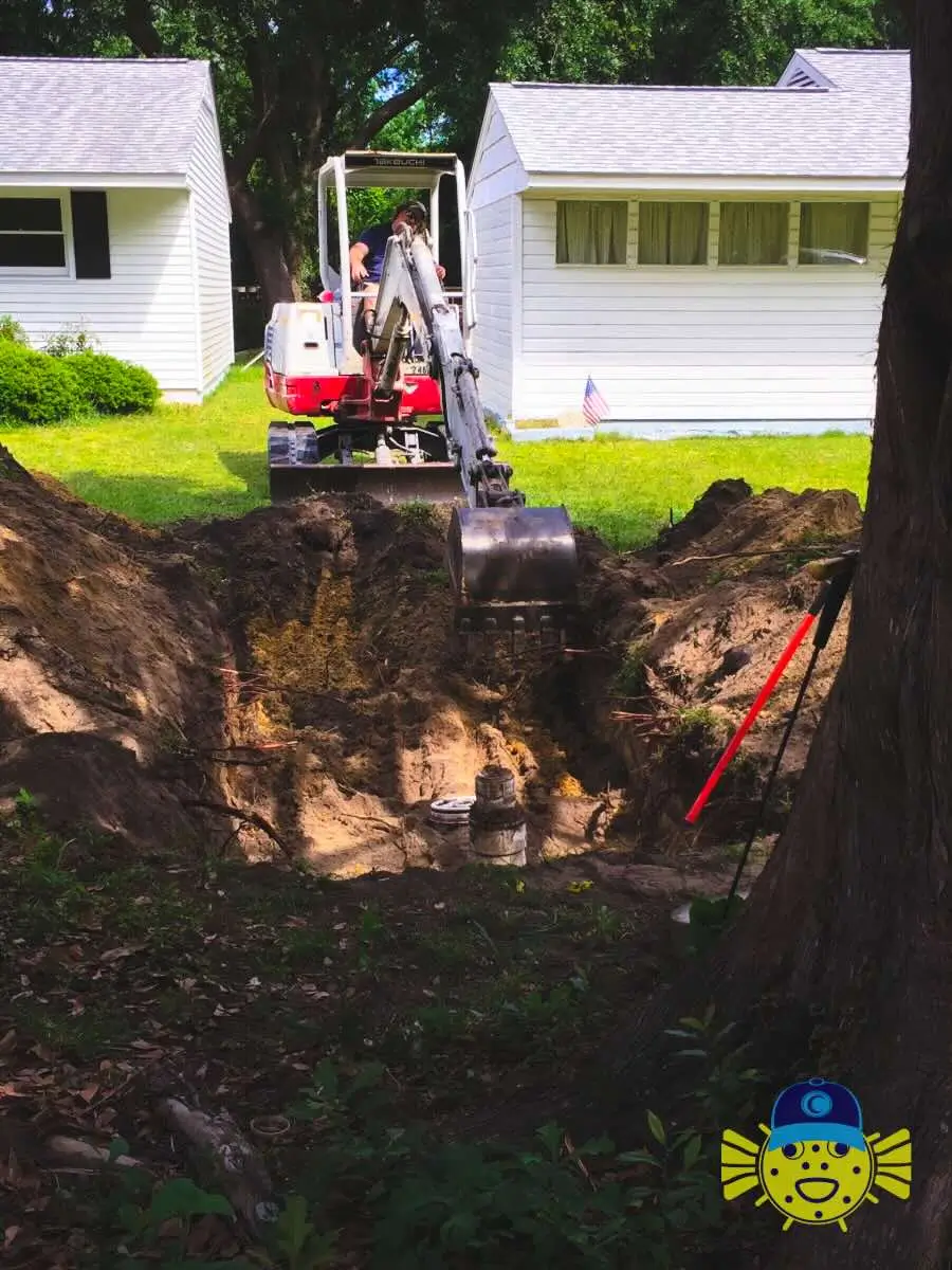 Swell Guy Plumbing plumber operating a compact excavator to dig a trench near residential houses in Hanahan, SC.