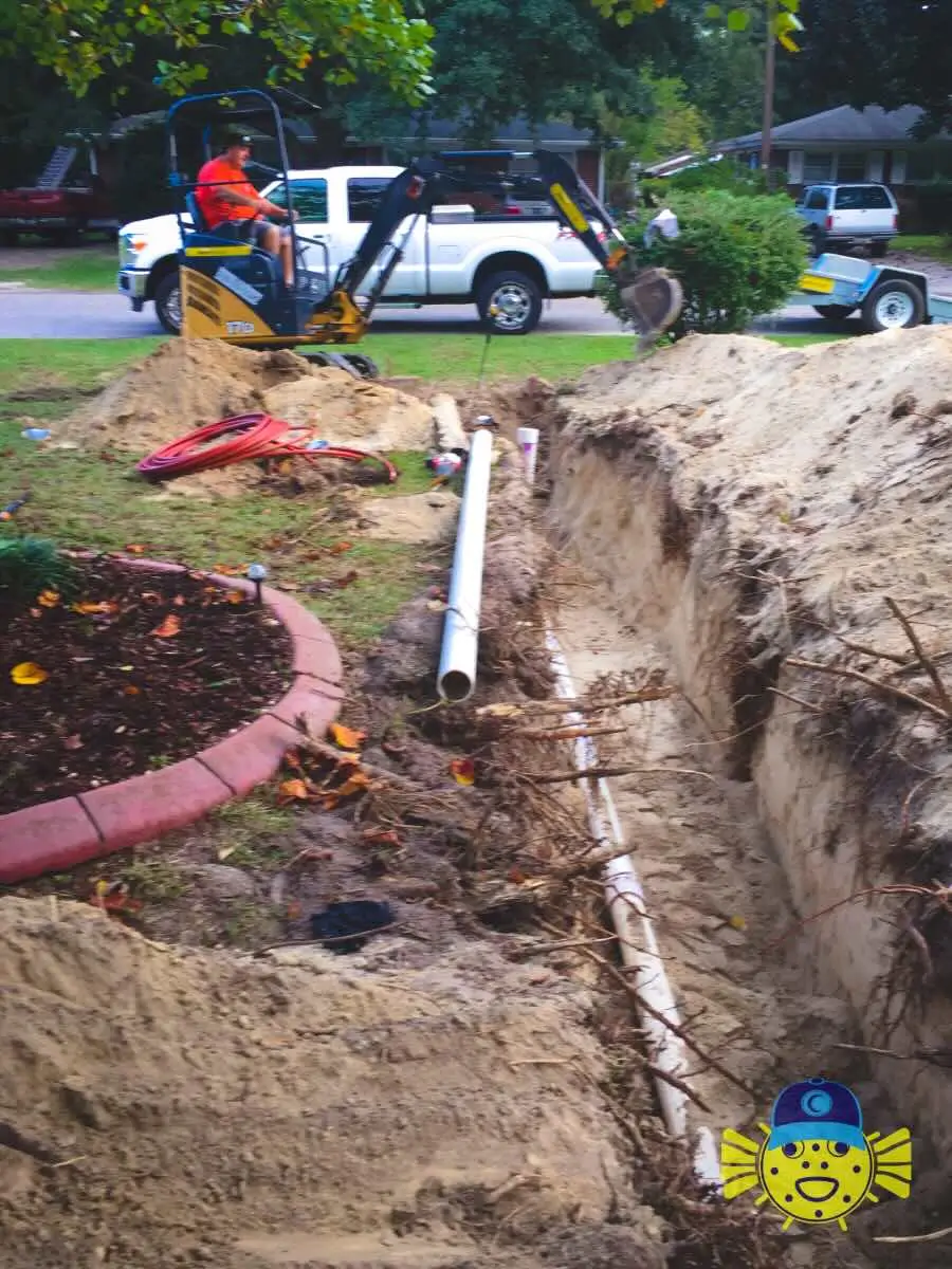Swell Guy Plumbing technician operating a mini excavator to dig a trench for a residential sewer line replacement in North Charleston, SC.