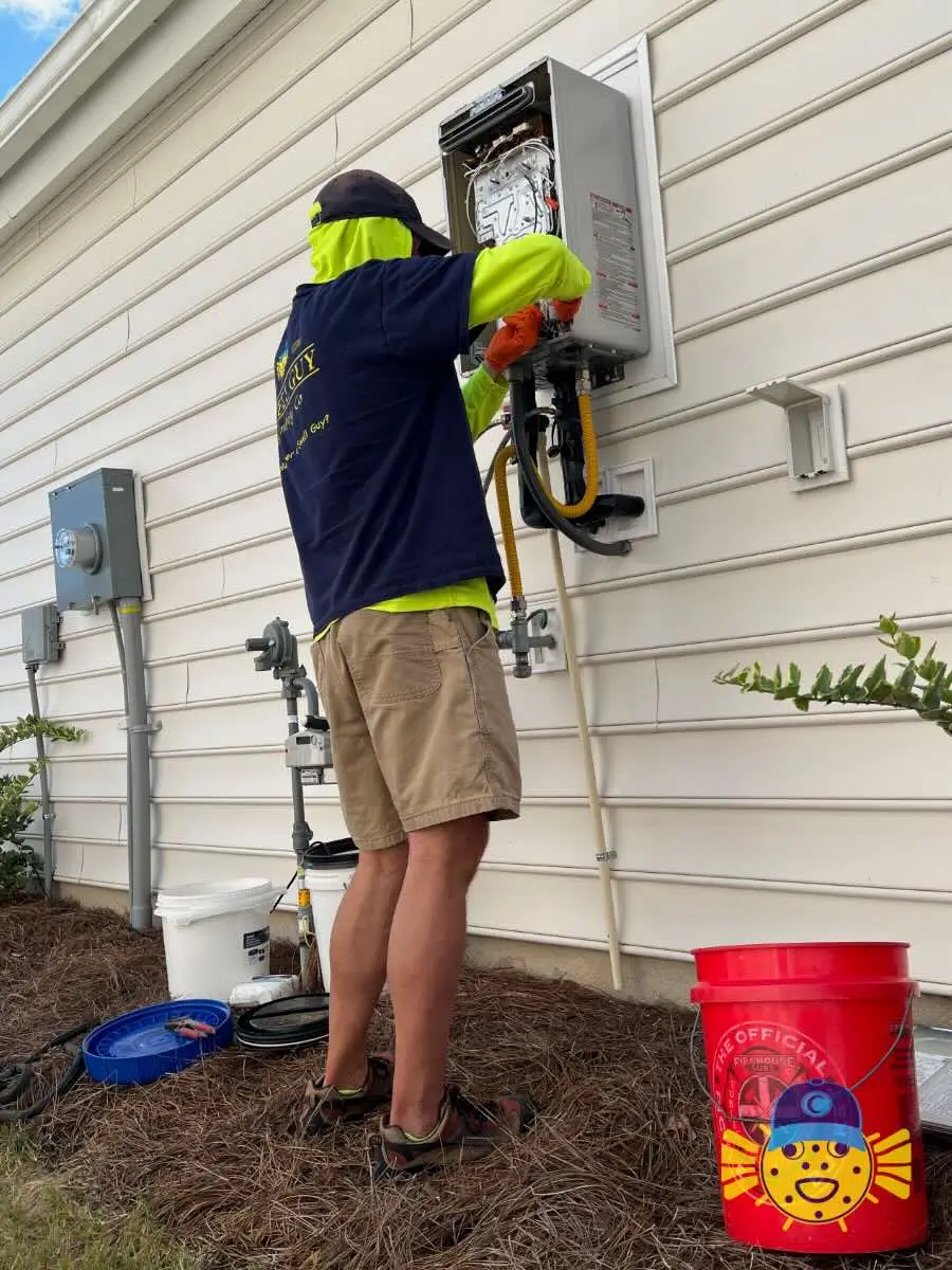 Swell Guy Plumbing technician servicing an exterior tankless water heater on a home in Summerville, SC.