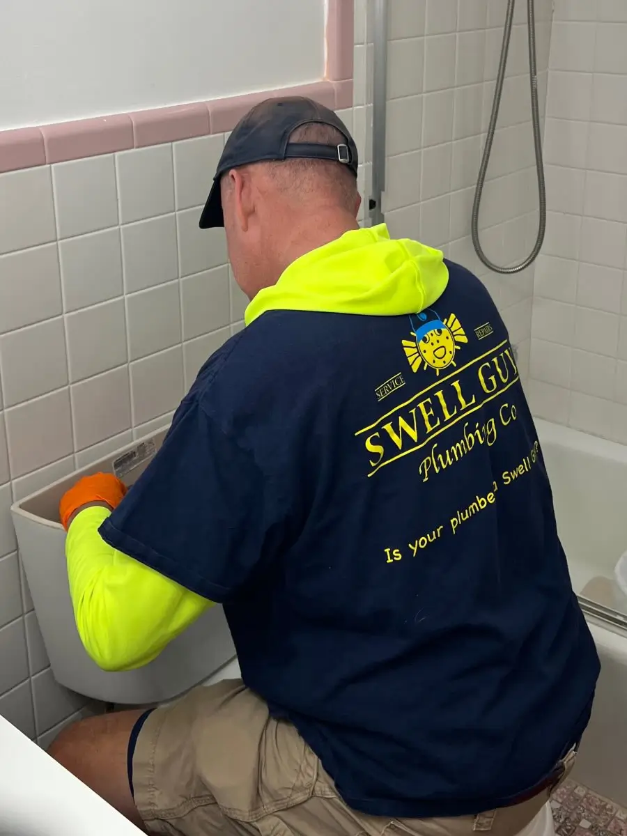 Swell Guy Plumbing technician repairing an open toilet tank in a bathroom in Moncks Corner, SC.
