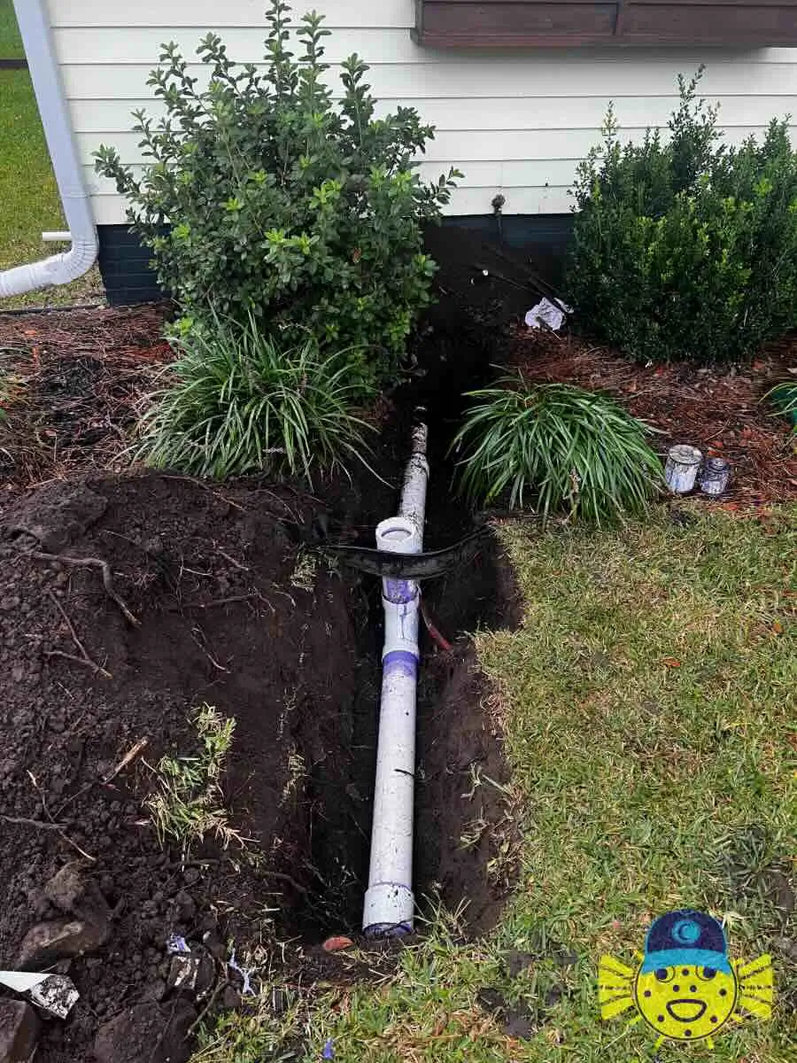 Newly installed white PVC two-way sewer cleanout pipe in a trench outside a house by Swell Guy Plumbing in North Charleston, SC.